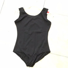 Load image into Gallery viewer, A sleeveless black dance leotard hanging on a white hanger against a tiled floor background.