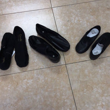 Load image into Gallery viewer, Three pairs of black slip-on dance or ballet shoes arranged on a tiled floor.