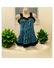 Load image into Gallery viewer, A black and blue zebra-print dance top with black trim, displayed on a mannequin torso between two small green plants.