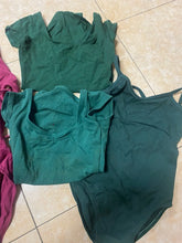 Load image into Gallery viewer, A collection of forest green dance leotards in various styles laid out on a tiled floor.