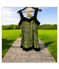 Load image into Gallery viewer, Ek green aur black zebra-print dance costume, jismein black trim detailing hai, hanger par latki hui hai aur background mein ek hara-bhara maidan hai.